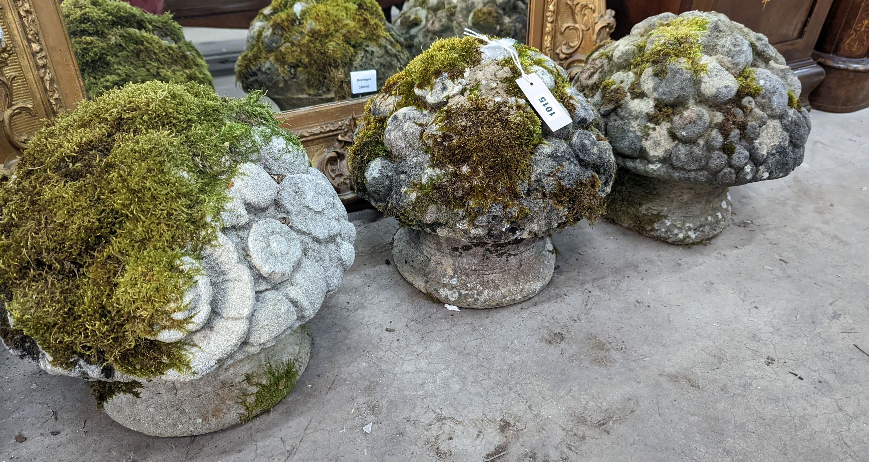 A set of three weathered reconstituted stone garden ornaments modelled as floral bunches, diameter 32cm, height 30cm